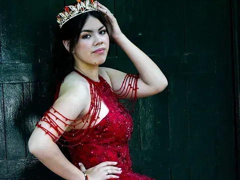 Una mujer con un vestido rojo y una tiara está parada frente a una pared verde.
