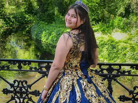 Una niña con un vestido azul y dorado está parada en un puente.