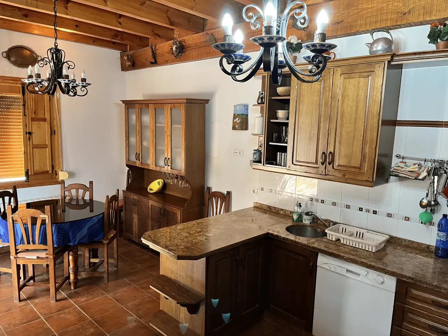 Una cocina rústica con gabinetes de madera, encimera de granito y mesa de comedor.