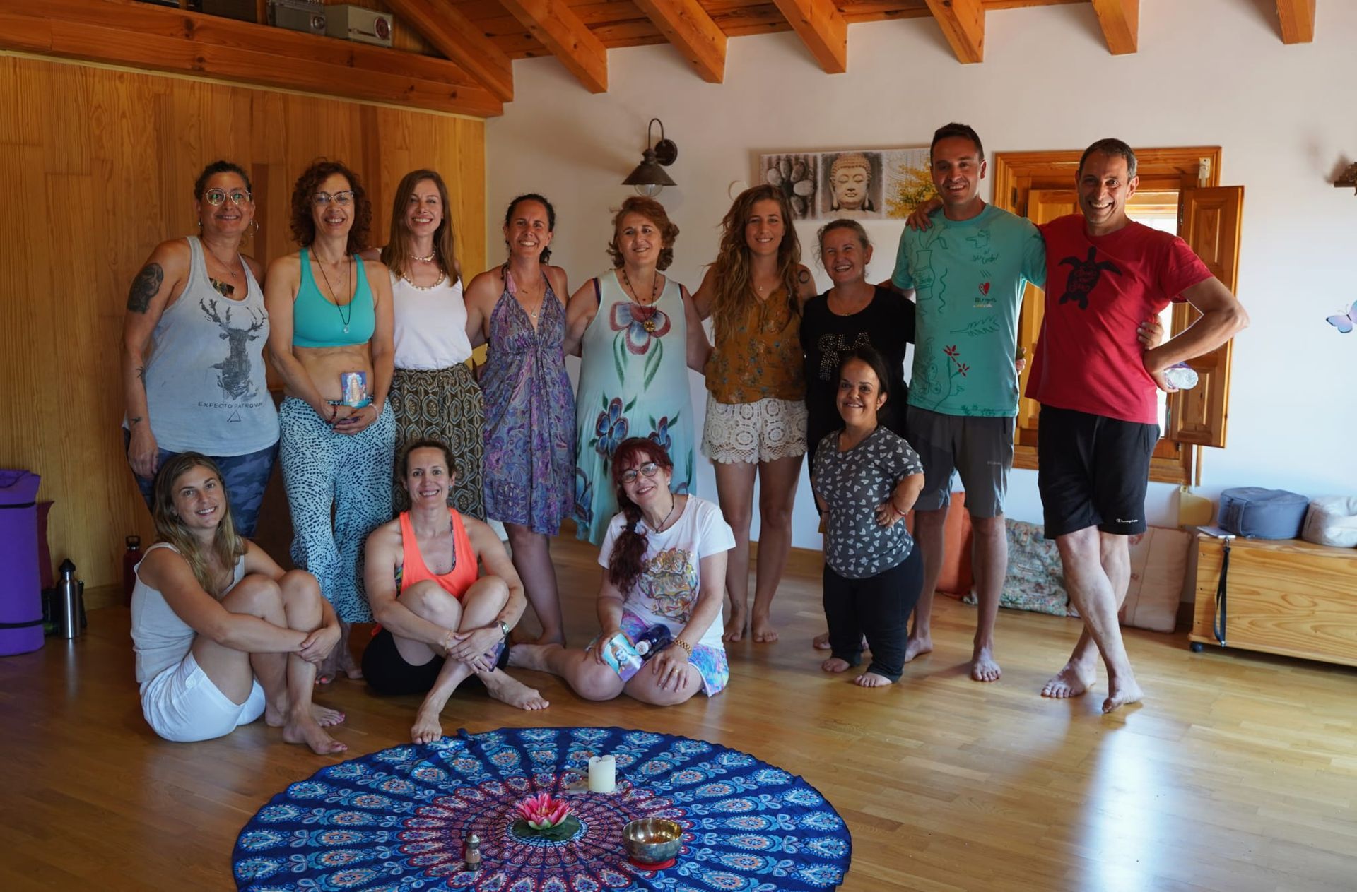 Grupo de personas sonriendo en una habitación soleada. Una alfombra de mandala azul en el centro.