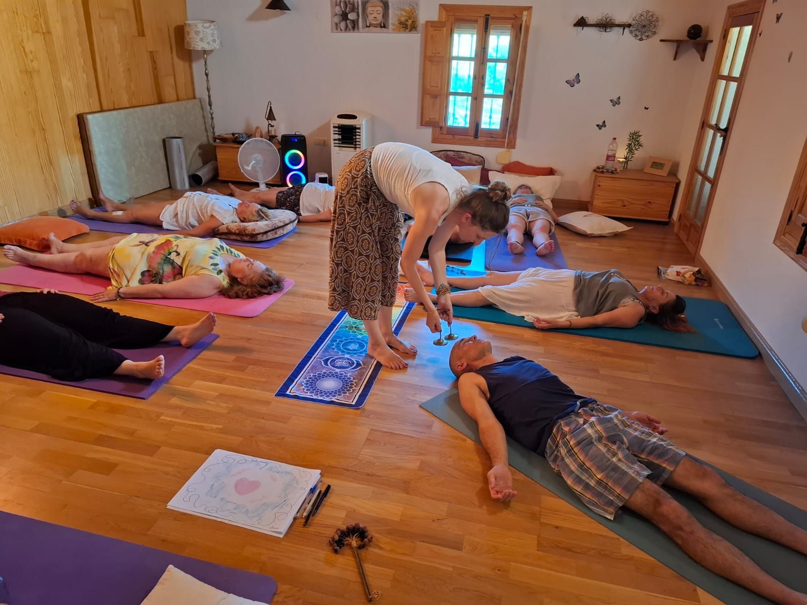 Clase de yoga: el instructor ajusta la postura del estudiante, las personas están acostadas sobre colchonetas en el interior.