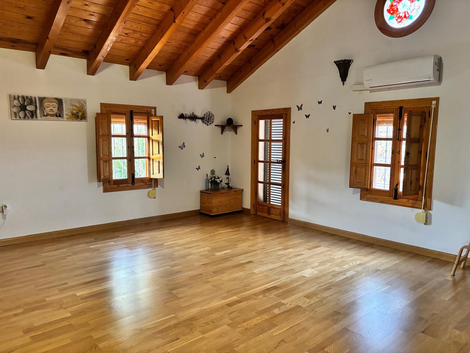 Habitación vacía con suelo, techo y marcos de ventanas de madera. Ventanas abiertas. Aire acondicionado en la pared.