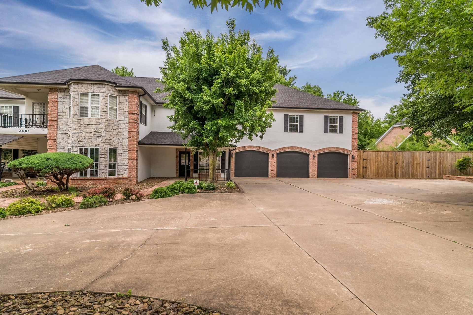 Two-story house with white siding, stone facade, and a three-car garage.