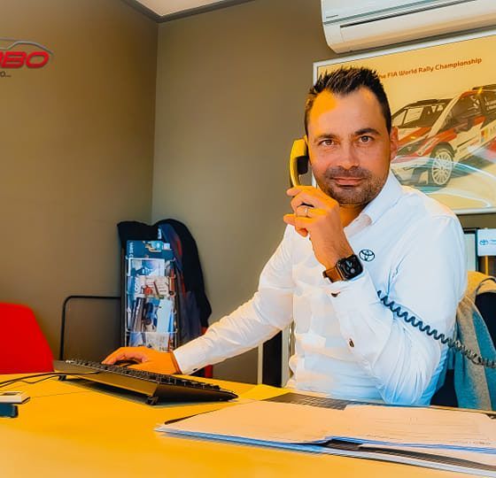 Un homme en chemise blanche, au téléphone, assis à un bureau dans un bureau.