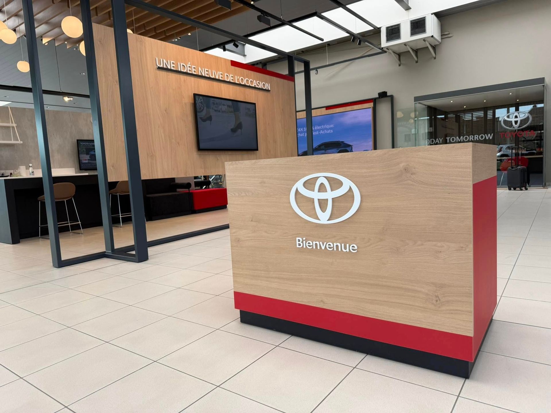Intérieur d'une concession Toyota avec comptoir d'accueil. Bois clair et touches de rouge ; logo Toyota affiché.