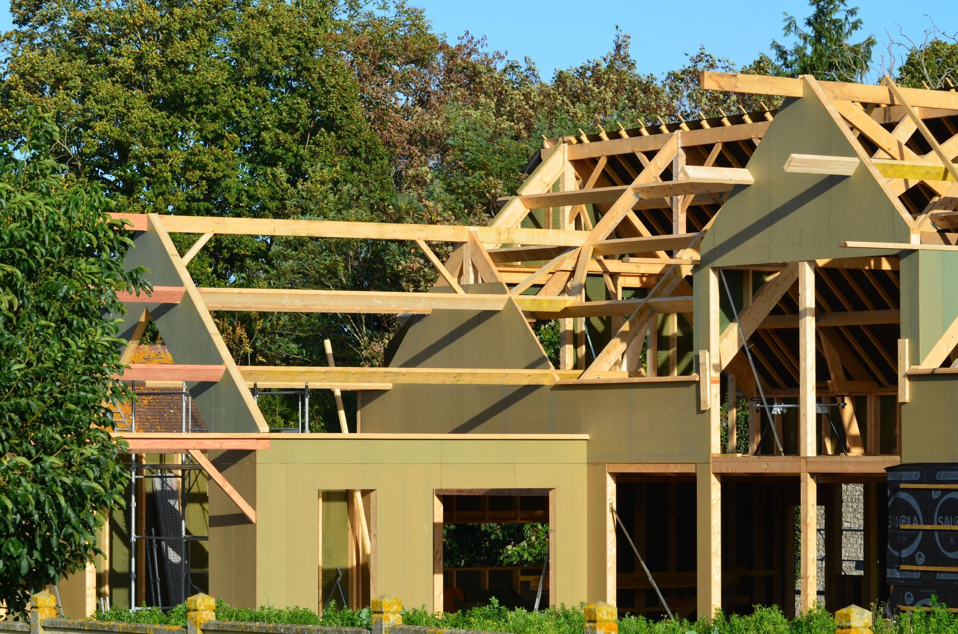 Maison en construction avec ossature bois apparente et murs non finis.