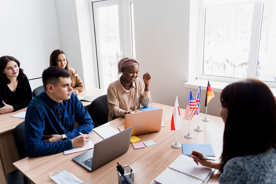 Un grupo de personas está sentado en una mesa con computadoras portátiles.