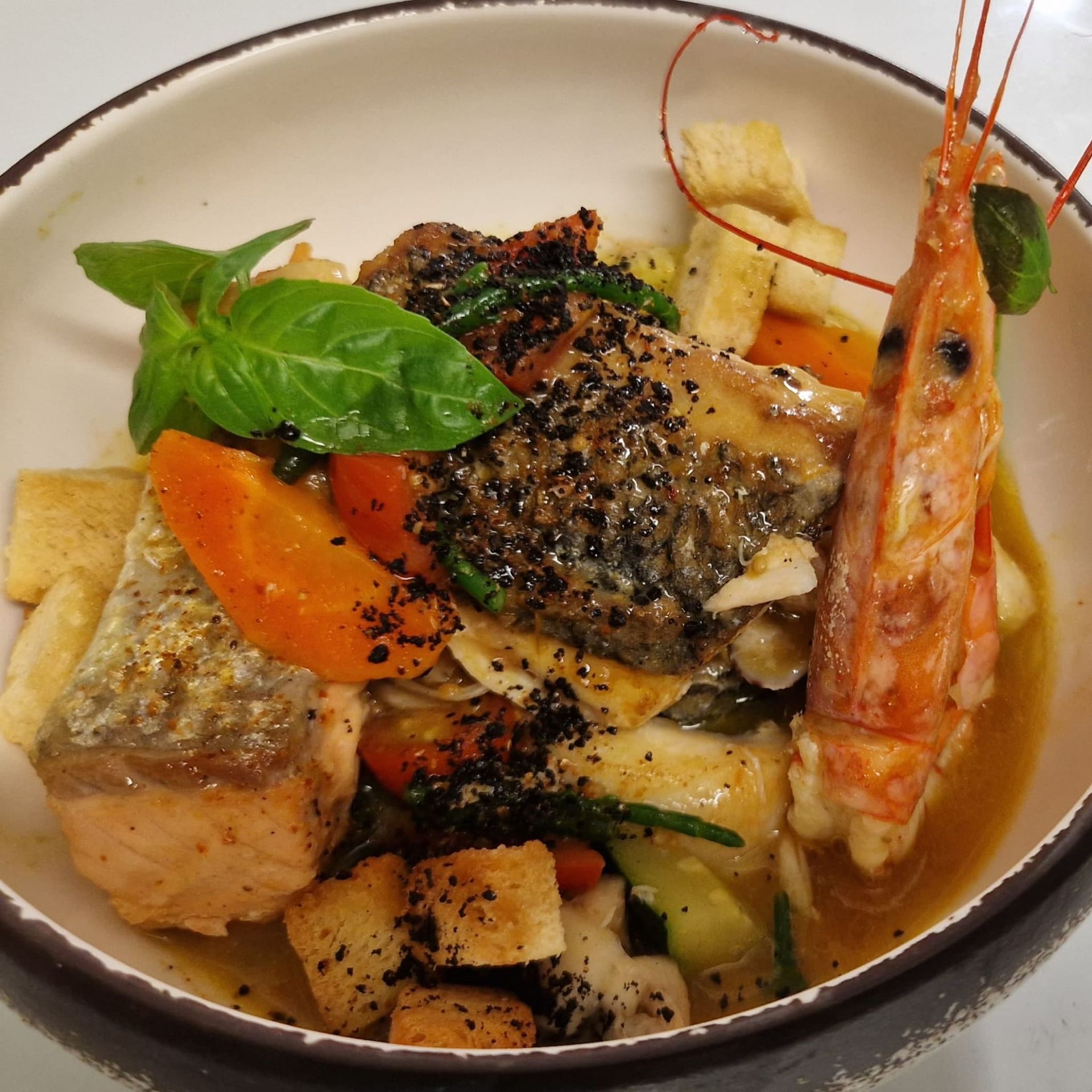 Des personnes se servent à manger sur une table en bois, où sont présentés divers plats comme des hamburgers et du poulet.