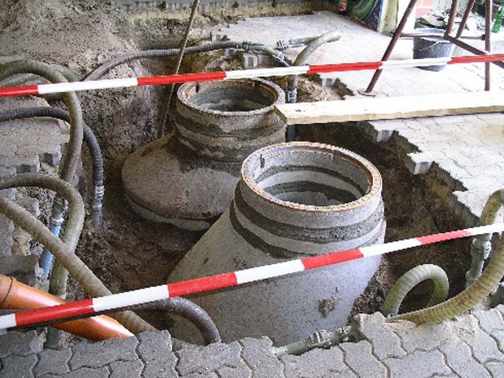 In einem Loch im Boden liegen mehrere Rohre.