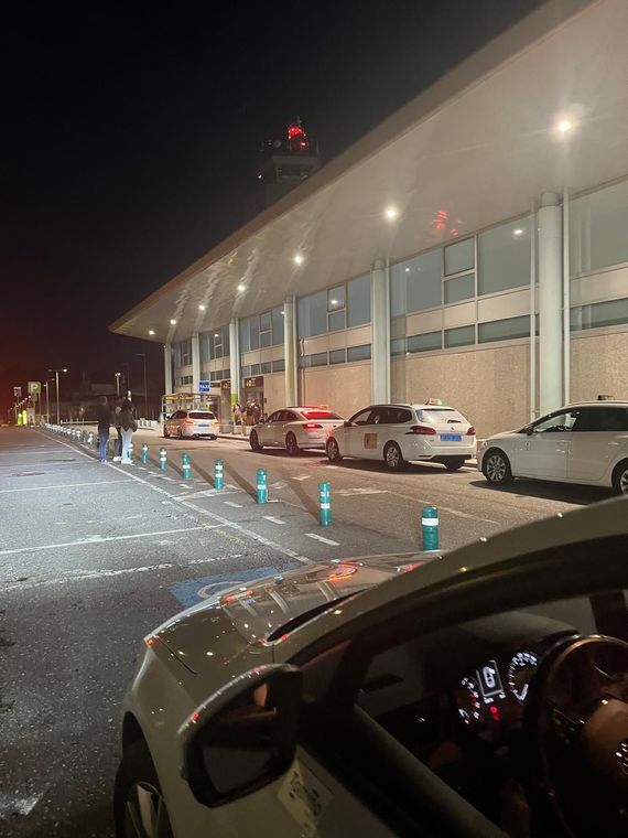 Mujer con mochila y maleta con ruedas caminando fuera del aeropuerto.