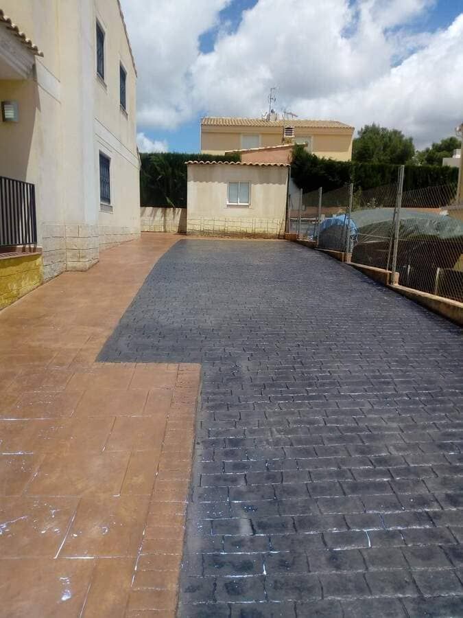 Un camino de entrada de ladrillo con un edificio al fondo.