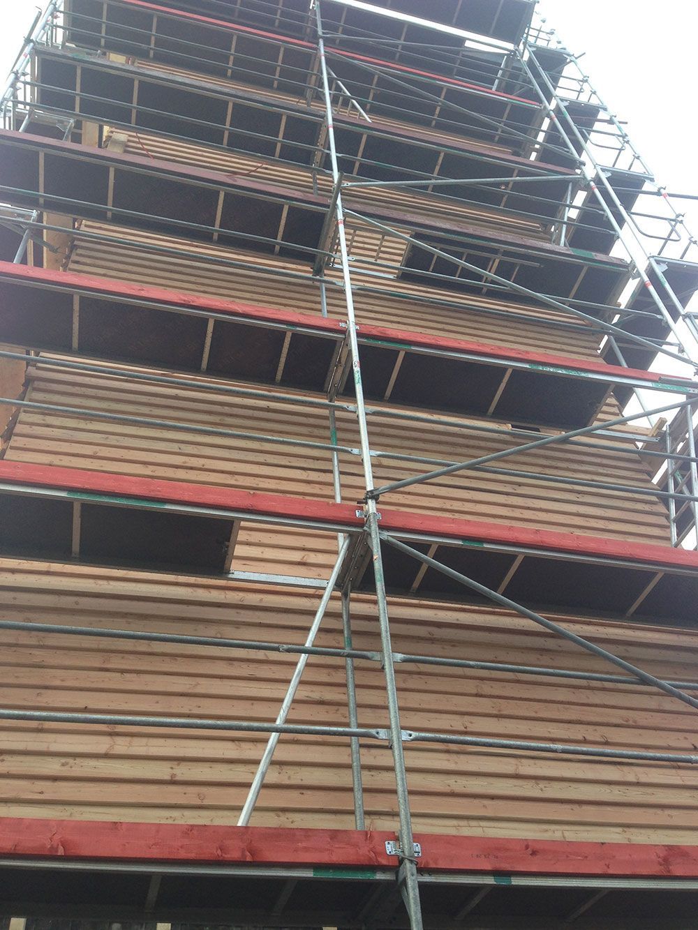 Ein hohes, im Bau befindliches Holzgebäude, umgeben von einem Gerüst mit mehreren Plattformen.