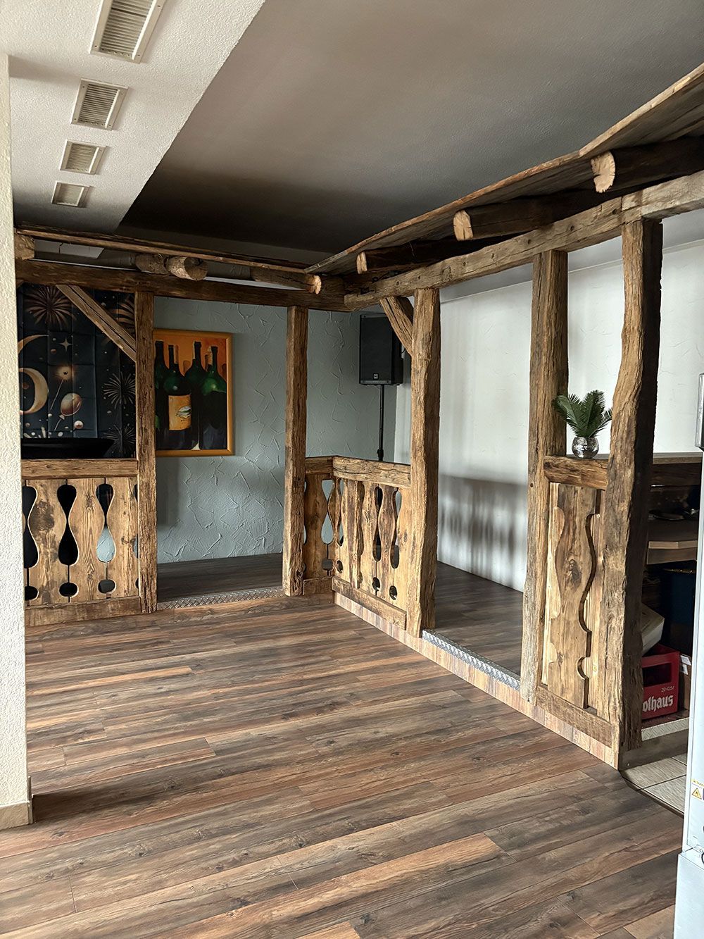 Rustikale Holzfachwerkkonstruktionen schaffen eine dekorative Bar oder Sitzecke im Innenbereich mit dunklem Holzboden und Einbauleuchten.
