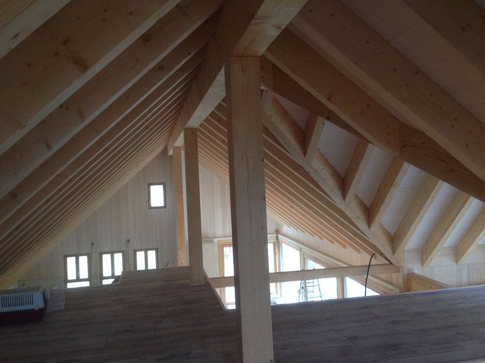 Ein im Bau befindlicher Dachboden mit einer hölzernen A-förmigen Dachkonstruktion und freiliegenden Balken.