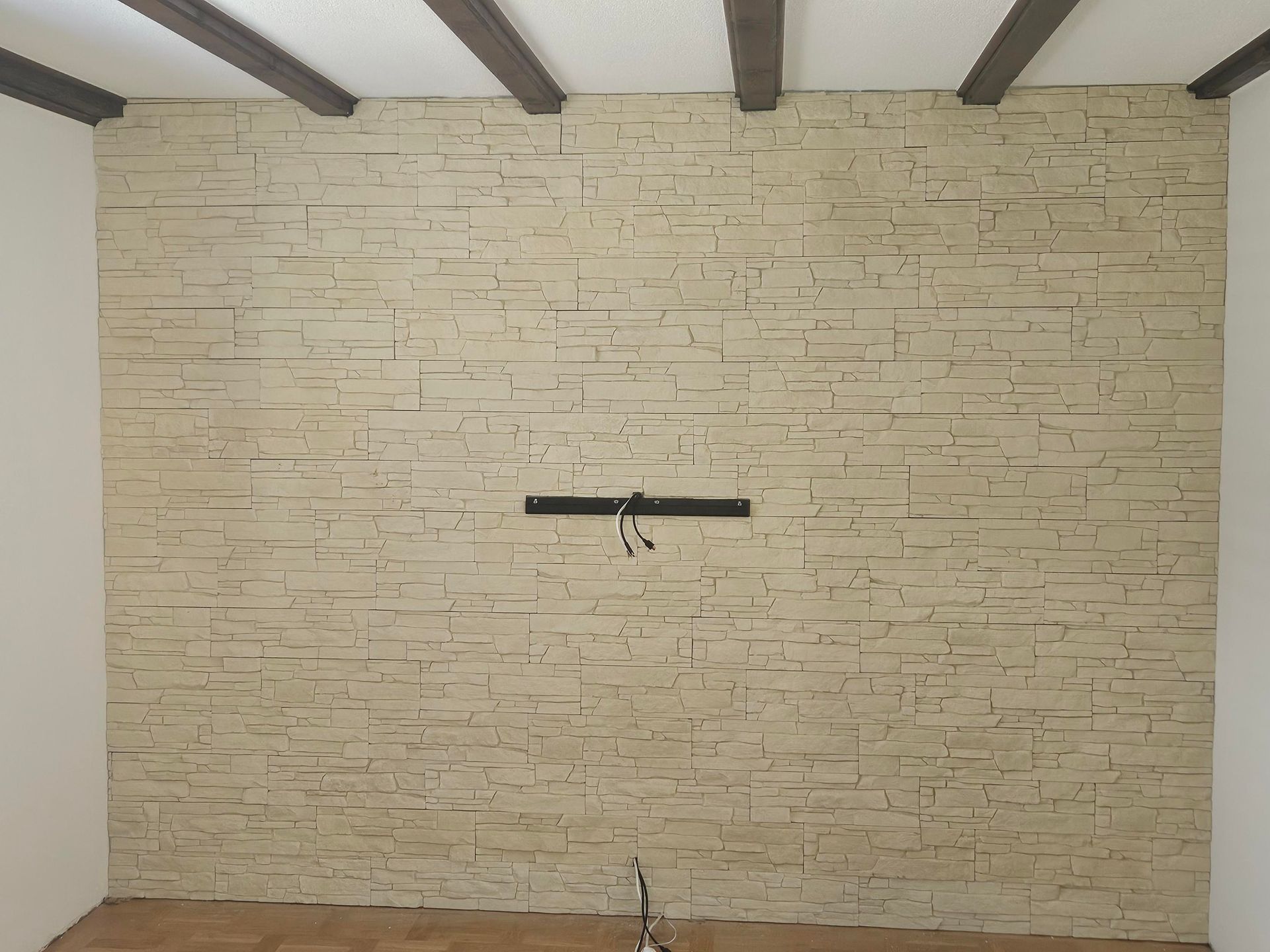 Maler im Overall mit einer Rolle an einer weißen Wand. Leiter, Fenster und Eimer sichtbar.