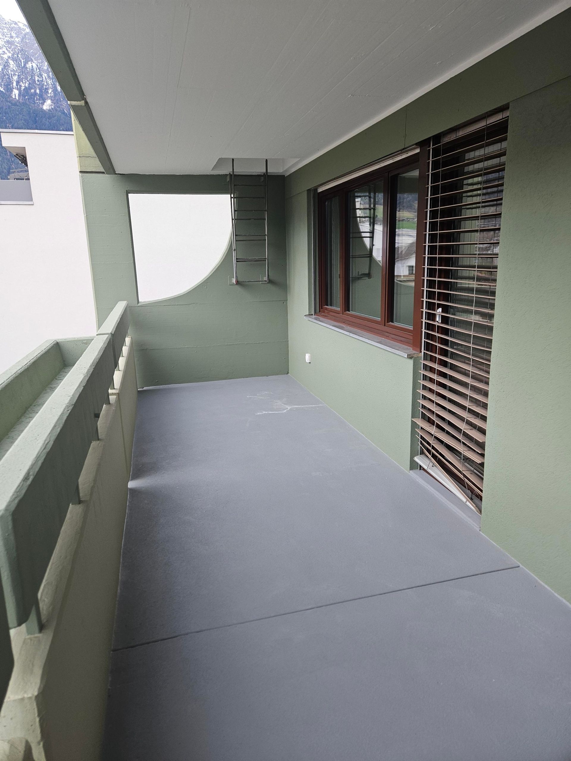 Person, die mit einer Kelle Gips auf eine Wand aufträgt, kniet neben einem Eimer Gips.