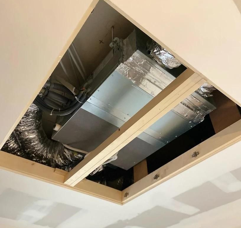 Ouverture au plafond laissant apparaître les conduits de ventilation à ossature en bois.