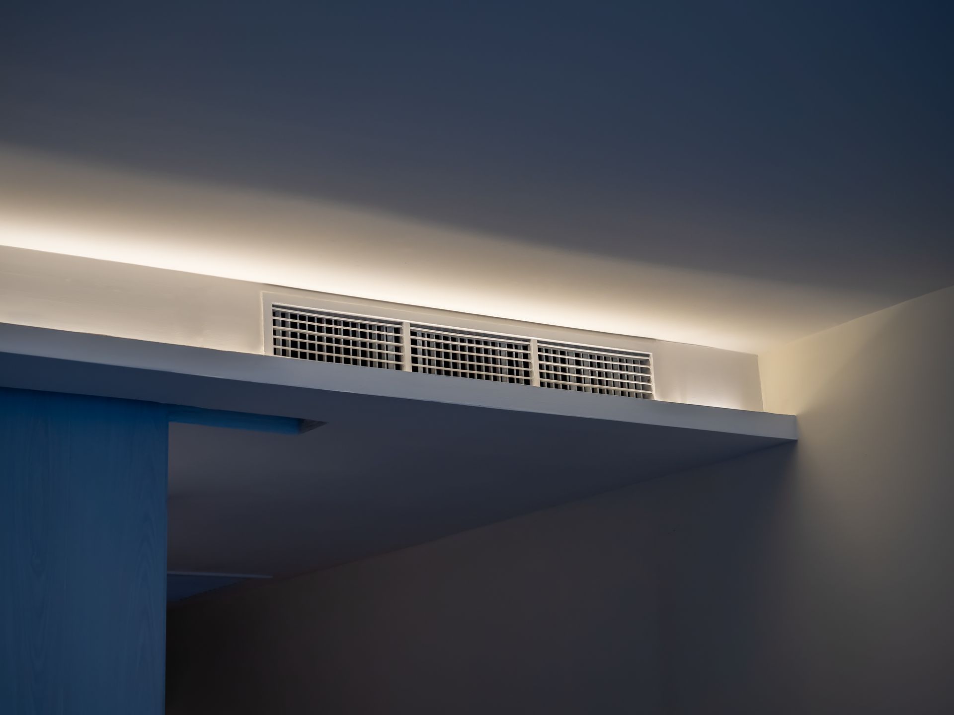 Grille d'aération encastrée dans un plafond blanc avec éclairage d'ambiance.
