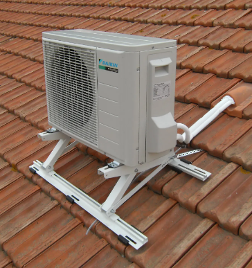 Unité de climatisation sur une structure métallique blanche, installée sur un toit de tuiles rouges.