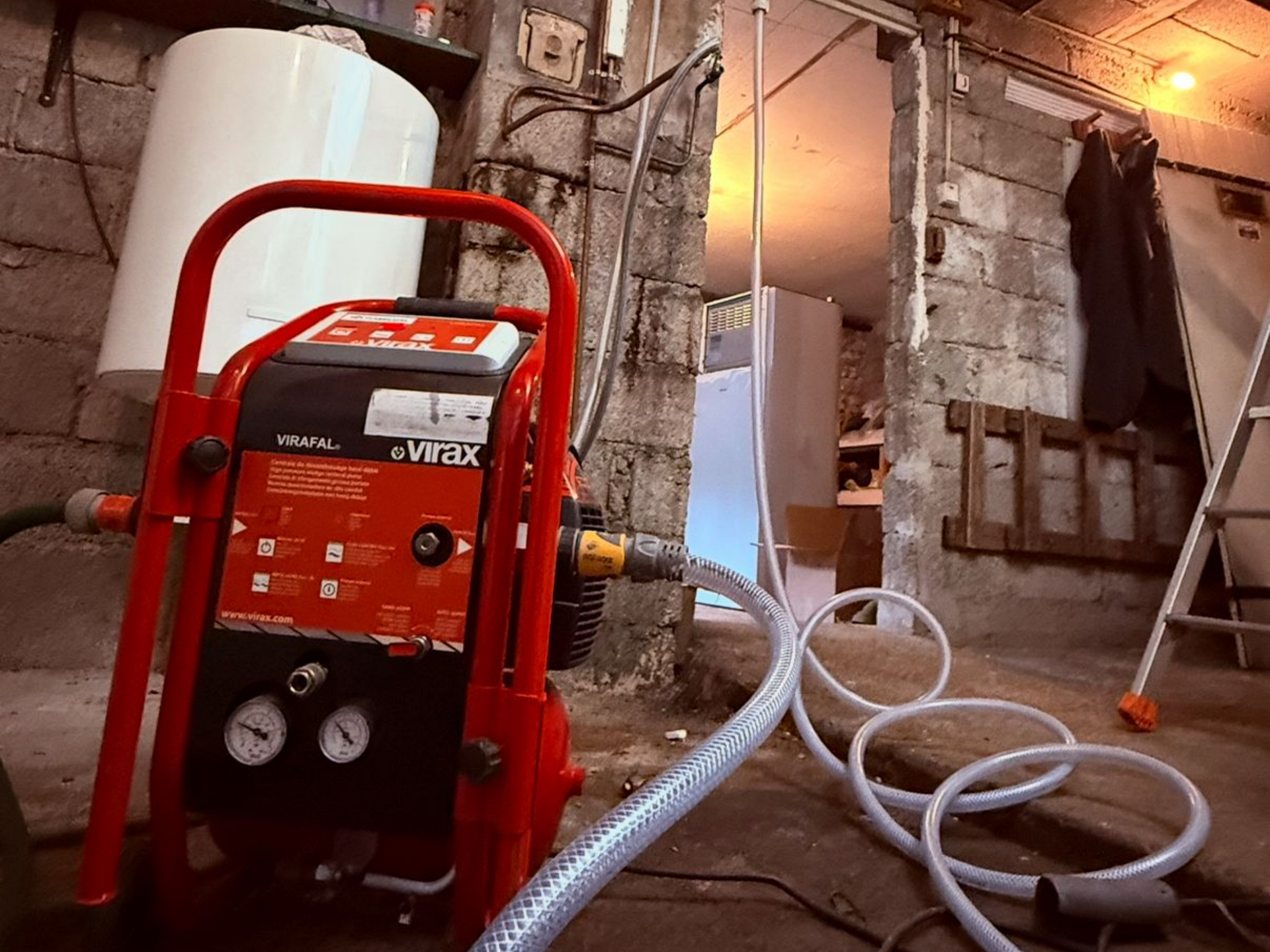 Pièce en travaux ; des tubes rouges sont installés au sol, probablement pour un chauffage radiant.