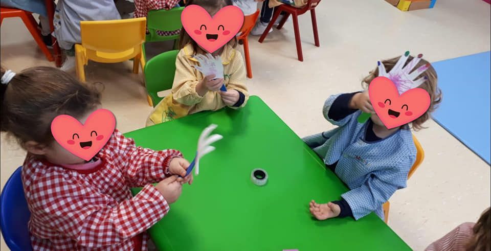 Un grupo de niños están sentados en una mesa con corazones en sus caras.