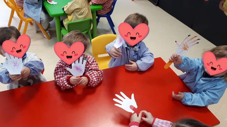 Un grupo de niños están sentados en una mesa con corazones en sus caras.