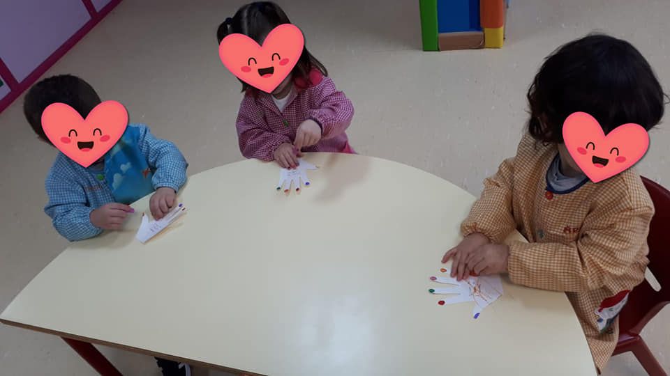Tres niños están sentados en una mesa con corazones en sus caras.