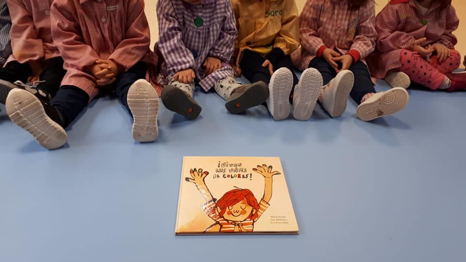 Un grupo de niños están sentados en el suelo mirando un libro.