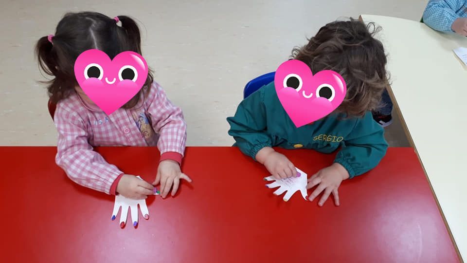 Dos niños están sentados en una mesa con corazones en sus caras.