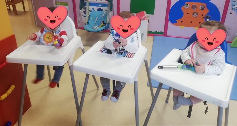 Tres bebés están sentados en sillas altas con corazones en sus caras.