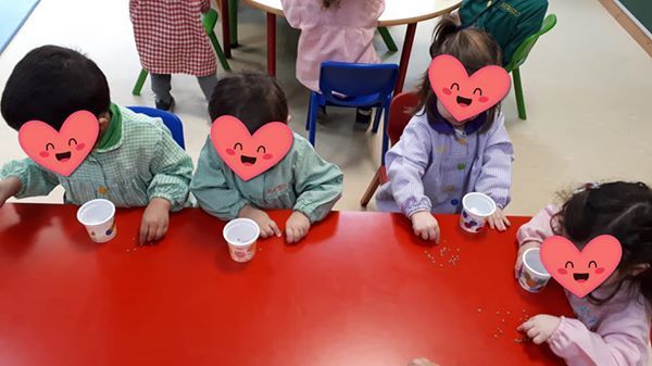 Un grupo de niños sentados en una mesa con corazones en sus caras.