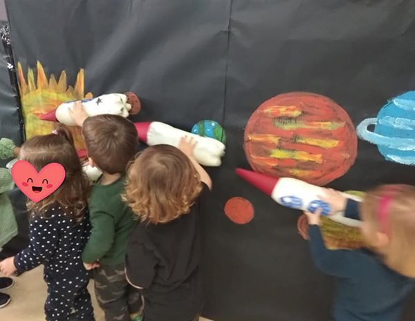 Un grupo de niños mira una pintura de planetas.