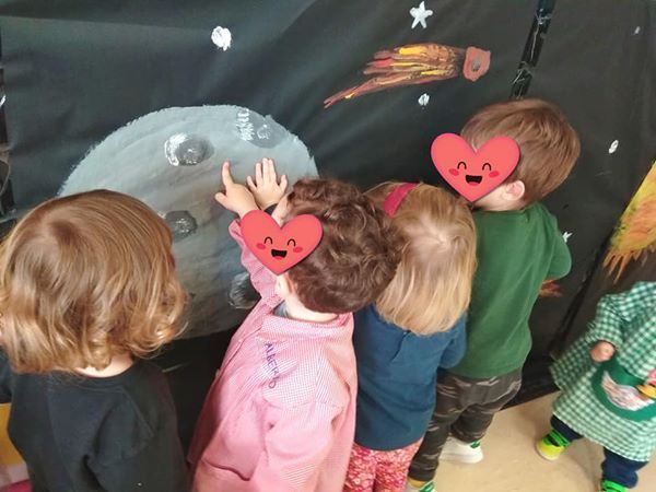 Un grupo de niños mira una pintura de un cometa.