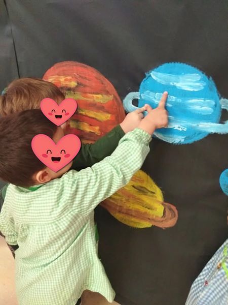 Un niño con un corazón en la cabeza señala un planeta.