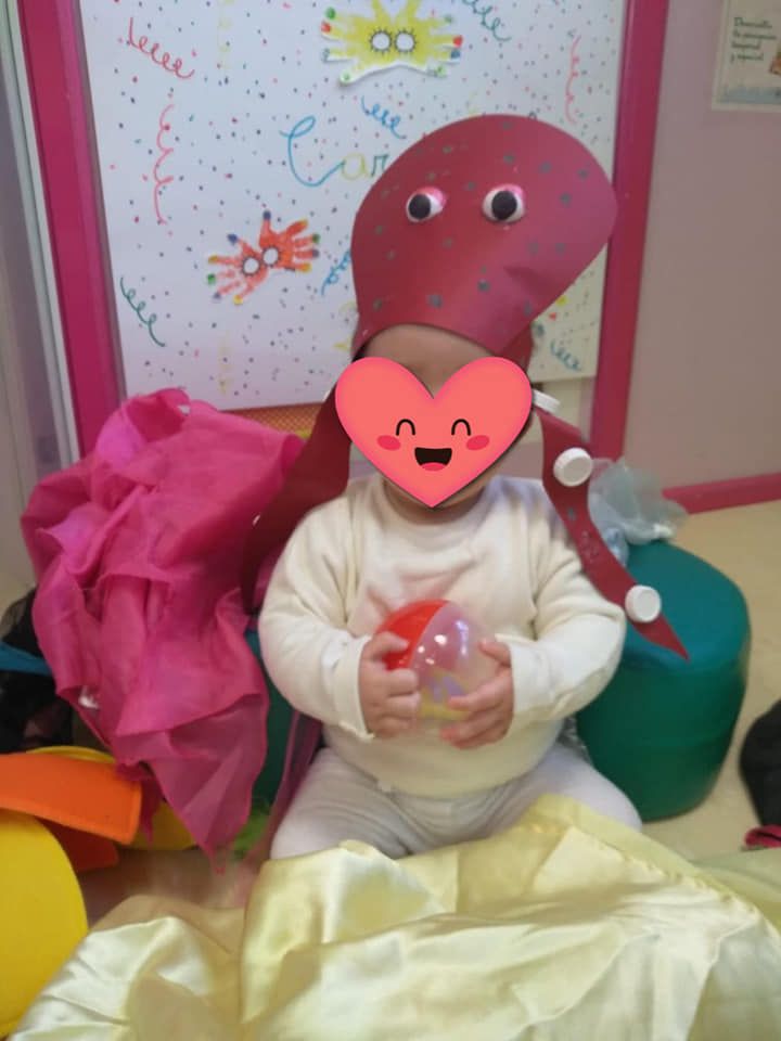 Un bebé disfrazado de pulpo sostiene una pelota.