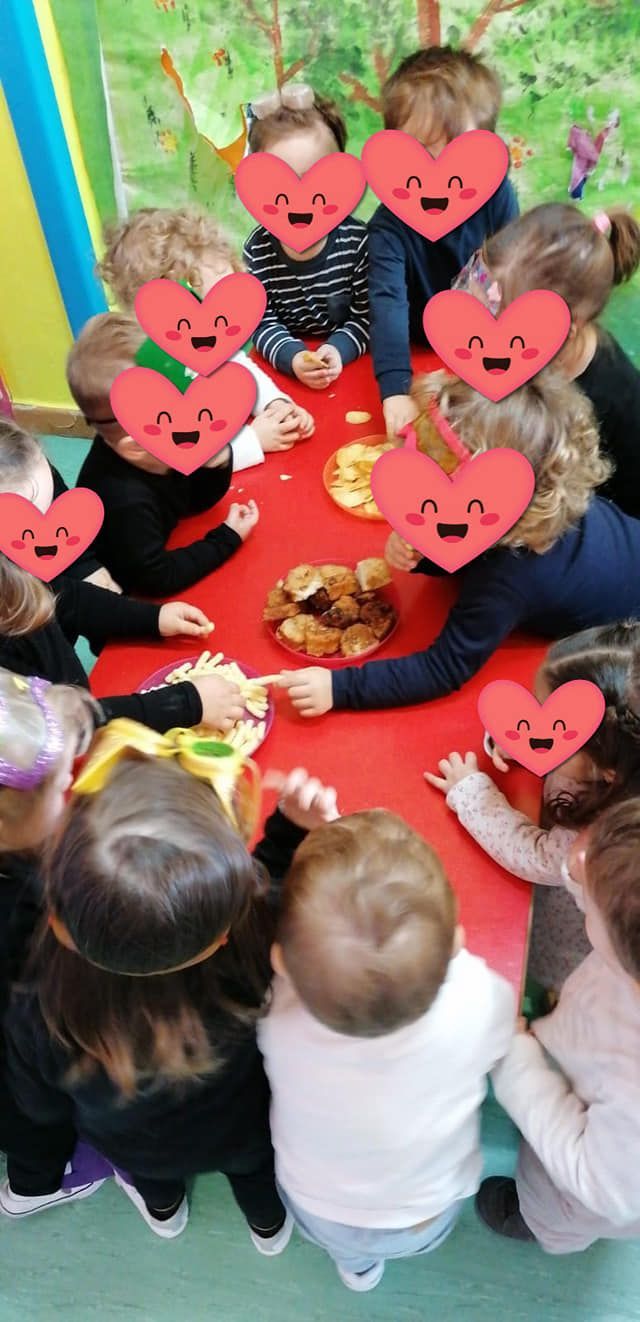 Un grupo de niños están sentados alrededor de una mesa con corazones en sus caras.