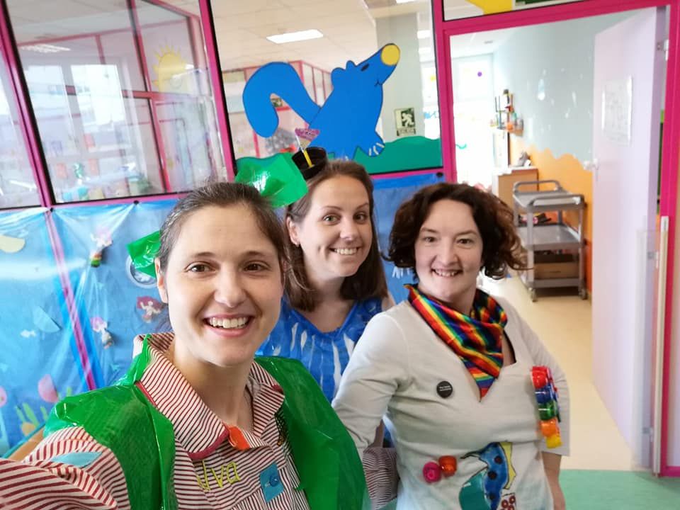 Tres mujeres están paradas una al lado de la otra en una habitación y sonriendo.