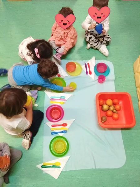 Un grupo de niños están sentados en el suelo jugando con platos y utensilios.