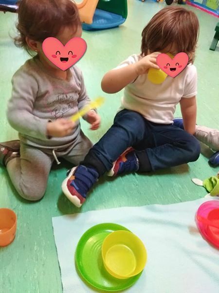 Dos niños con corazones en sus caras se sientan en el suelo.