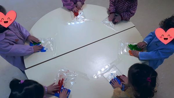 Un grupo de niños están sentados alrededor de una mesa con corazones en sus caras.