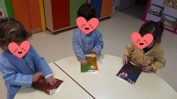 Tres niños están sentados en una mesa con corazones en sus caras.