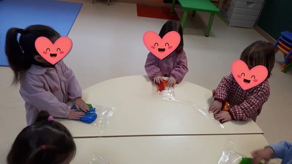 Un grupo de niños están sentados en una mesa con corazones en sus caras.
