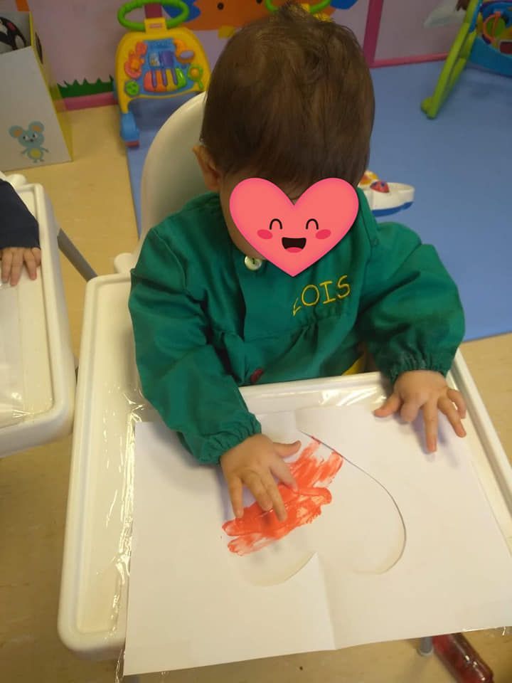 Un niño con un corazón en su cara está sentado en una silla alta.