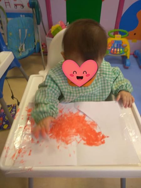 Un bebé con un corazón en la cara está sentado en una silla alta.