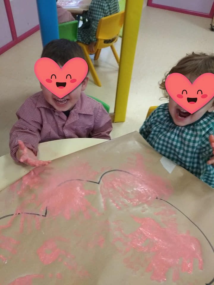Dos niños con corazones en sus caras están sentados en una mesa.