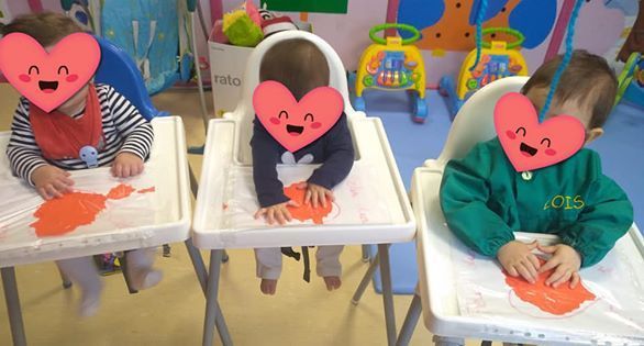 Tres bebés están sentados en sillas altas con corazones en sus caras.