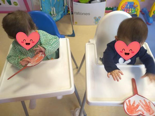 Dos bebés en sillas altas con corazones en sus caras.