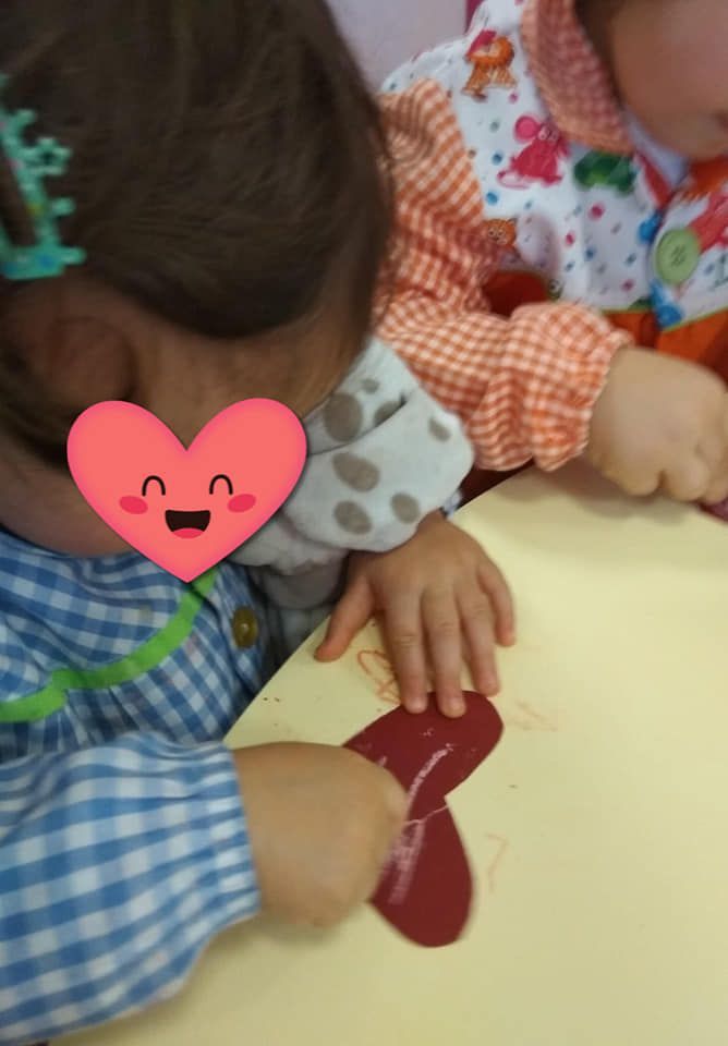 Una niña con un corazón en la cabeza está jugando con un corazón rojo.