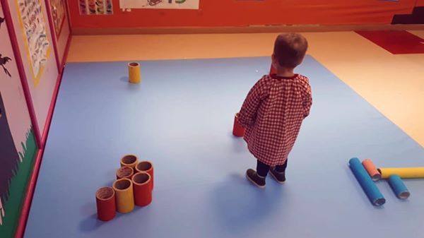 Un niño está de pie sobre una alfombra azul en una habitación.