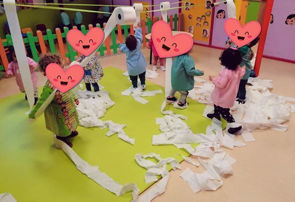 Un grupo de niños está jugando con papel higiénico en una habitación.